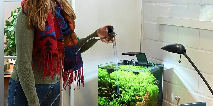 Femme qui aspire le fond de son aquarium